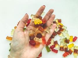 helle, schmackhafte, ungewöhnliche Gummibärchen aus Gelatine in verschiedenen Formen. Bonbons liegen auf der Hand einer Frau. Mädchen behandelt Freunde auf einer Party mit Süßigkeiten. saftiges leckeres dessert foto