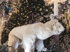 Weihnachtsdekorationen. Ein Spielzeug-Eisbär steht neben einem künstlichen Weihnachtsbaum. Heiligabend. stilisierte Ausstellung für Besucher. Eulen und andere Vögel fliegen in der Nähe foto