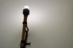 lampe, dekorative wandlampe in form einer alten alten fackel, beleuchtung mit einer led-glühbirne gegen eine weiße wand aus steinbeton foto