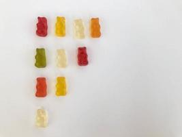 Gummibärchen liegen auf einem weißen, matten Hintergrund. Gummibärchen sind nach Farbe angeordnet. Demonstration, Diagramm des Abnehmens und Ansteigens. visuelle Mathematik auf spielerische Weise foto