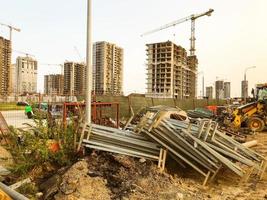 Baulandschaft. verlassene Baustelle. unnötiges Baumaterial liegt im Gebüsch. verlassene hohe Häuser. unvollendetes Viertel für Menschenleben foto