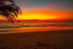 Silhouette des wunderschönen Sonnenuntergangs am Meeresstrand mit Palme für Reisen in der Urlaubszeit, foto