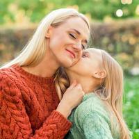 Tochter küsst ihre junge Mutter foto