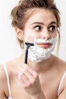 Frau, die ihr Gesicht mit Rasiermesser rasiert foto