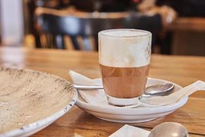 Cappuccino-Kaffee in transparentem Glas auf Teller in einem Café im mediterranen Stil foto