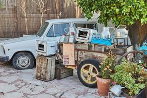 altes Auto, Schubkarre mit antiken Utensilien aus Holz und Metall, um den Innenhof des Cafés zu schmücken foto