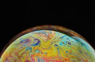 Raum der virtuellen Realität mit abstraktem mehrfarbigem psychedelischem Planeten. Closeup Seifenblase wie ein fremder Planet auf schwarzem Hintergrund foto