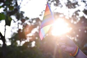 regenbogenfahne und armbänder in den händen halten, weicher und selektiver fokus, konzept für lgbtq-geschlechtsfeiern und aufruf an alle menschen, die menschenrechte im stolzmonat auf der ganzen welt zu respektieren. foto