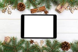 digitales tablet-modell mit rustikalen weihnachtlichen hölzernen hintergrunddekorationen für app-präsentation. draufsicht mit kopierraum foto