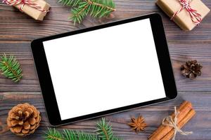 digitales tablet-modell mit rustikalen weihnachtlichen hölzernen hintergrunddekorationen für app-präsentation. draufsicht mit kopierraum foto