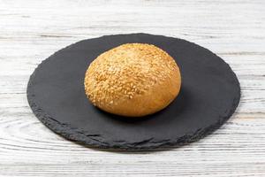 Frisch gebackenes Brot oder Brötchen mit Sesam und Sonnenblumenkernen auf Schiefertafel foto