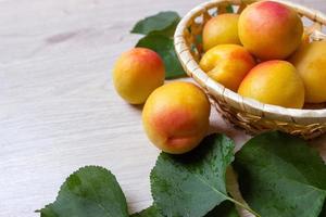 frische Aprikosen im Korb auf einem Holztisch foto