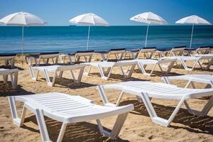 schöner leerer strand mit reihen von sonnenliegen unter strohschirmen foto