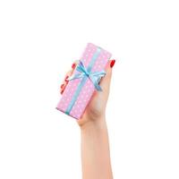 frauenhände geben eingewickeltes weihnachts- oder anderes handgemachtes geschenk in rosa papier mit blauem band. isoliert auf weißem Hintergrund, Ansicht von oben. Thanksgiving-Geschenkbox-Konzept foto