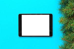 leeres bildschirmtablett auf blauem hintergrund, weihnachtszeit draufsicht foto