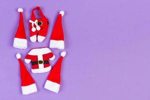 Draufsicht auf rote Weihnachtsmützen und Kleidung auf buntem Hintergrund. frohes weihnachtskonzept mit kopienraum foto