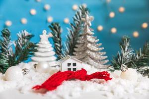 abstrakter Adventsweihnachtshintergrund. Spielzeughaus mit gestricktem Schal mit Schnee- und Winterdekorationsverzierungen auf blauem Hintergrund. weihnachten mit familienkonzept zu hause. foto