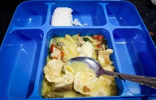 Indonesisches Essen hat Soto Betawi, das mit Reis serviert wird, der in einem blauen Essbereich serviert wird foto