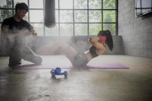 asiatische männliche und weibliche boxtrainer mit sandsäcken im fitnessstudio. foto