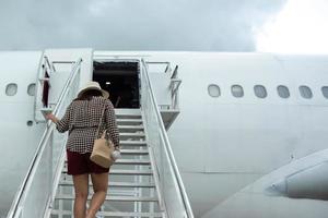 junge reisende frau, die ins flugzeug einsteigt. foto