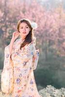 reise, urlaub in japan konzept, junge asiatin, die morgens im park traditionellen japanischen kimono trägt. foto