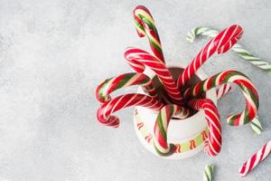 viele weihnachtszuckerstangen in einem becher auf grauem hintergrund mit kopienraum. helles festliches weihnachtskaramell. foto