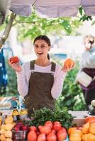 junge Verkäuferin, die selbst angebaute Tomaten in den Händen hält foto