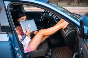 junge Frau mit Laptop in ihrem Auto foto