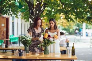 Zwei junge Frauen bilden einen schönen festlichen Blumenstrauß. foto