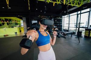 Frau mit Brille der virtuellen Realität, die mit Hanteln trainiert foto