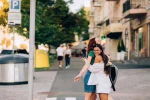 glückliches treffen zweier freunde, die sich auf der straße umarmen foto