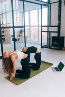 zwei charmante sportlerinnen, machen yoga-posen, übungen zu hause