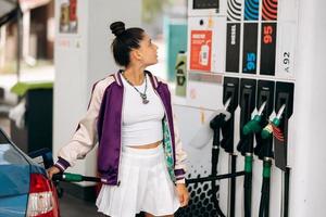 Frau, die ihr Auto an einer Tankstelle mit Kraftstoff befüllt foto