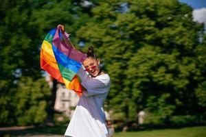 junge frau, die lgbt-stolzfahne im park schwenkt. foto