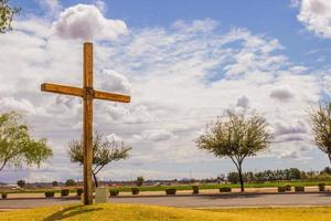 großes Holzkreuz auf grasbewachsenem Hügel neben der Straße foto