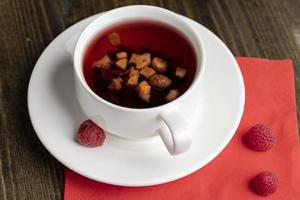 roter Himbeertee mit Fruchtstückchen und Beeren foto