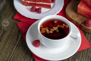 roter Himbeertee mit Fruchtstückchen und Beeren foto