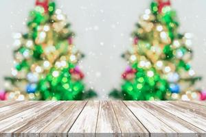 leere hölzerne tischplatte mit unscharfem weihnachtsbaum mit bokeh hellem hintergrund foto