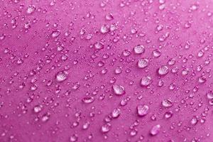 Wassertropfen auf magentafarbenem Regenschirm
