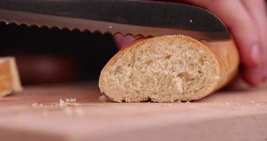 Schneiden eines Weizenbaguettes auf einem Schneidebrett foto