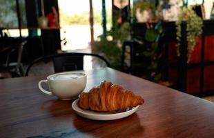 Croissant und Kaffee zum Frühstück auf dem Tisch foto