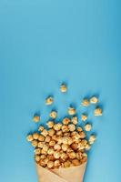 Popcorn in Karamellglasur in einem Papierumschlag auf blauem Hintergrund. foto