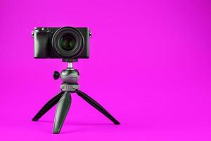 professionelle kamera auf einem stativ, auf einem rosa hintergrund. Nehmen Sie Videos und Fotos für Ihren Blog oder Bericht auf.
