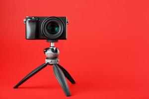 professionelle Kamera auf einem Stativ, auf rotem Hintergrund. Nehmen Sie Videos und Fotos für Ihren Blog, Reportage auf