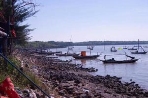 blick auf den felsigen strand, wo fischerboote in kenjeran surabaya lehnen foto