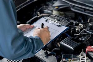 nahaufnahme handwagenservicepersonal prüfen motorstörungen und fehlercheckliste im maschinenraum, autoservicekonzept foto
