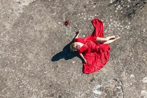 Luftbild auf Mädchen in rotem Kleid, das auf Felsen oder Betonruinen liegt foto