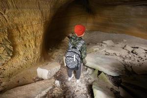 junge tragen rucksack erkunden kalksteinhöhle am berg in pidkamin, ukraine. foto