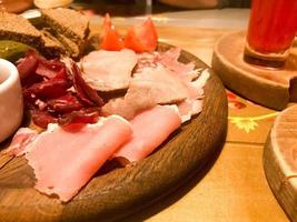 Fleischsnack mit Alkohol aus Fleisch, Schinken, Basturma mit Soße auf Holzständern auf dem Tisch in einem Café, einer Bar, einem Restaurant foto