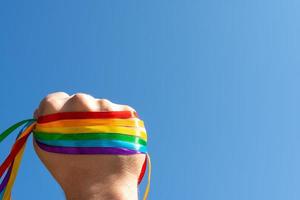 hand gegen den himmel erhoben in einem zeichen der einheit und stärke lgbt regenbogenfahnenarmband foto